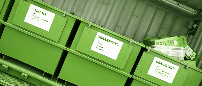 Inuti den mobila återvinningscentral står flera stora avfallskärl på rad
