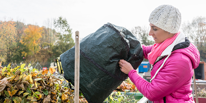 En kvinna tömmer sitt trädgårdsavfall i en container på en återvinningscentral.