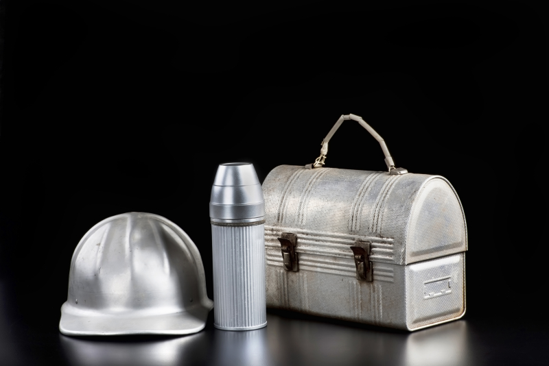 Tre föremål i metall. En bygghjälm, en termos och en väska.