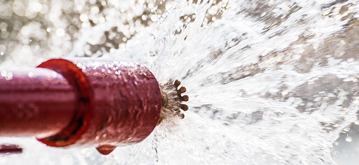 Rött rör med sprinkler i ena änden som sprutar vatten