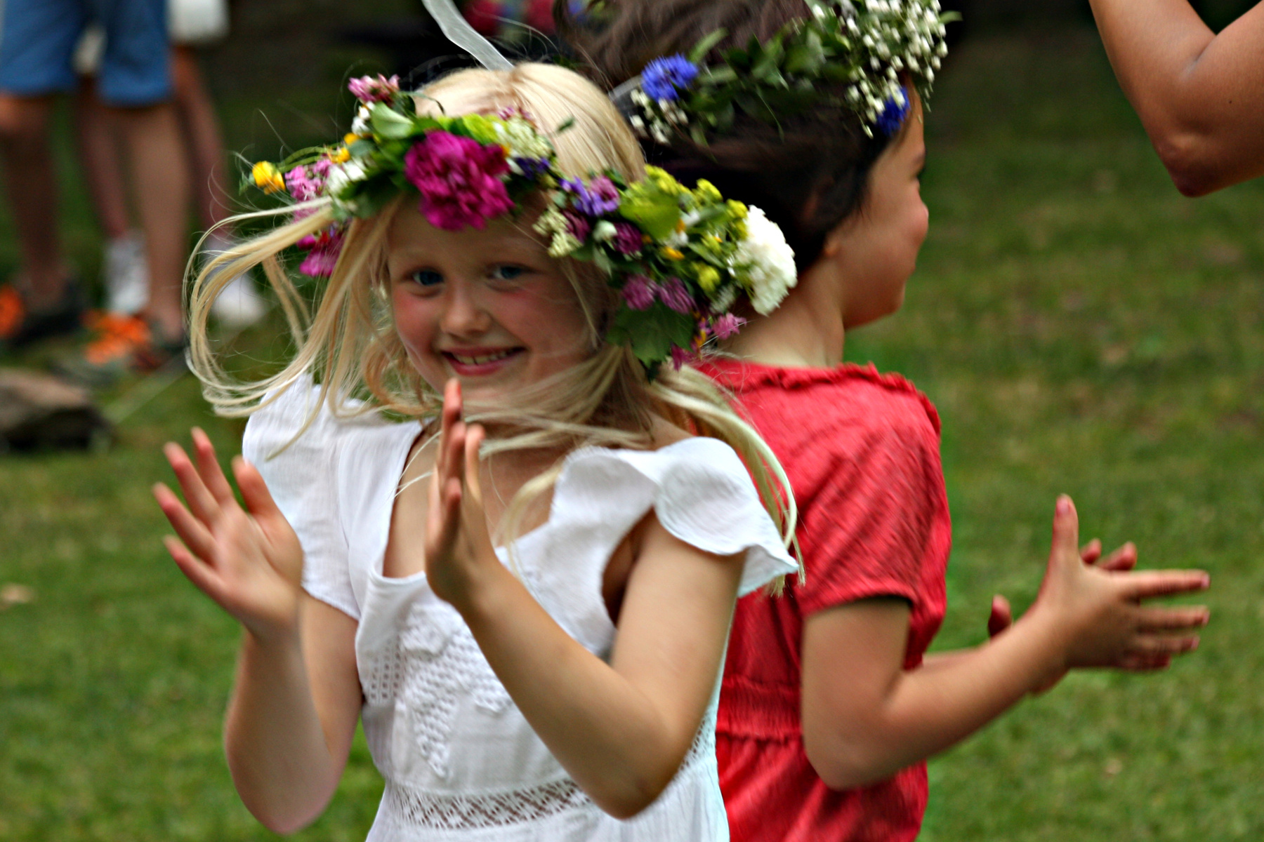 Midsommar, två flickor dansar med blomsterkransar i håret